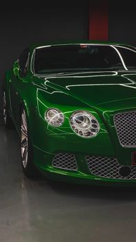 Elegant green luxury sports car parked in a Dubai garage.