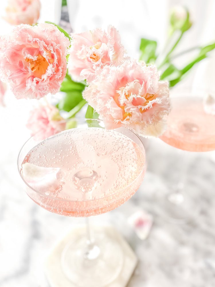 Close-Up Shot Of A Glass Of Wine Beside Pink Flowers