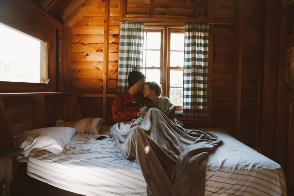 Couple embracing in cozy wooden cabin, creating a warm and intimate atmosphere.