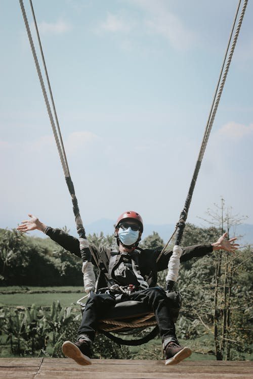 A Man in Black Jacket Riding a Swing