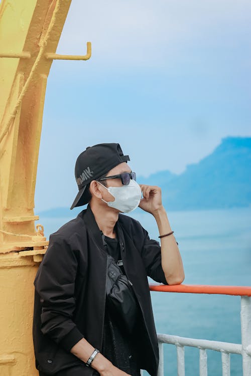 A Man in Black Jacket Leaning on the Railing