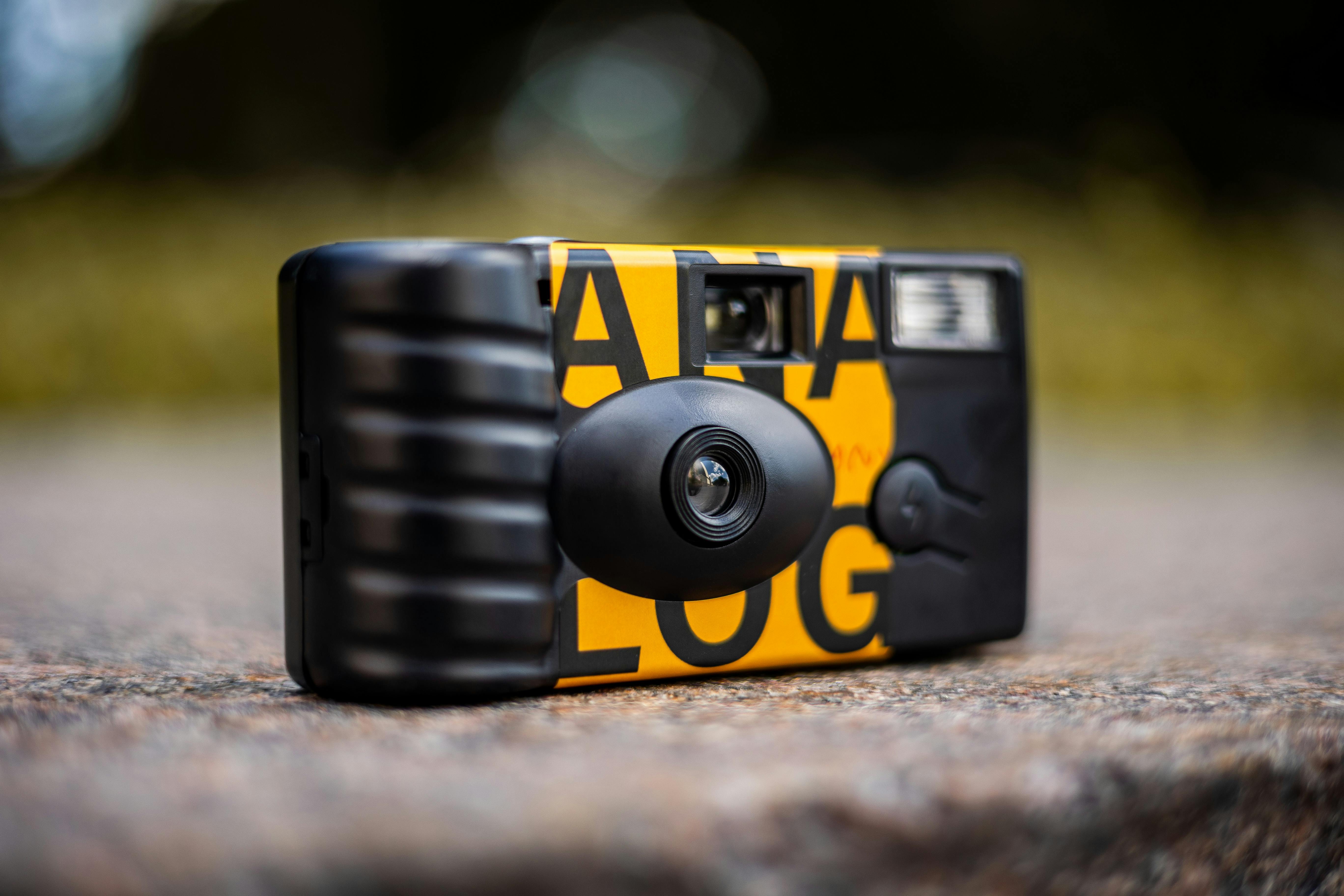 Close-up shot of a colorful disposable camera with shallow focus outdoors.
