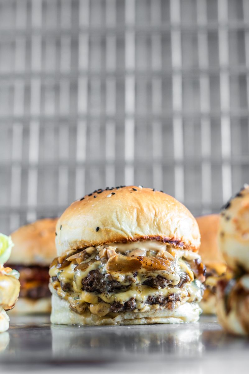 A griddled smash burger with melted cheese on a sesame bun