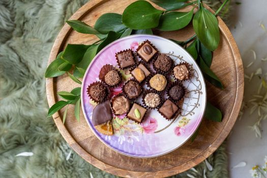 Delicious assortment of gourmet chocolates elegantly arranged on a floral-patterned plate, perfect for dessert lovers.