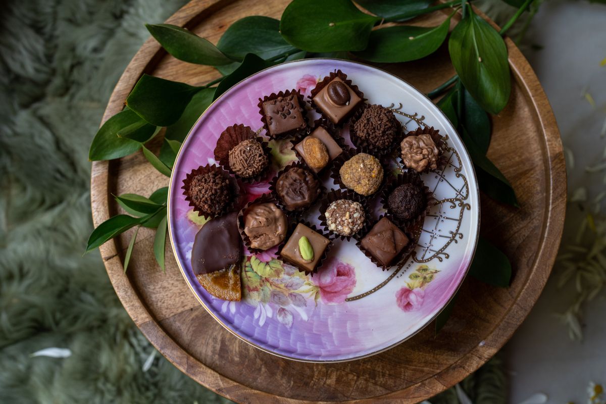 Delicious assortment of gourmet chocolates on a vintage floral plate, perfect for desserts and sweets lovers.