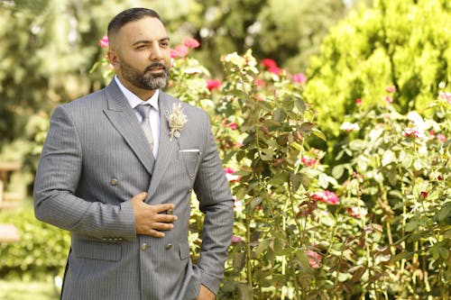 A Man in Gray Suit Jacket Standing Near Green Plants