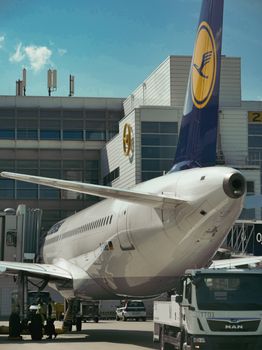 A commercial airplane at an airport gate being prepared for departure with a service vehicle nearby.