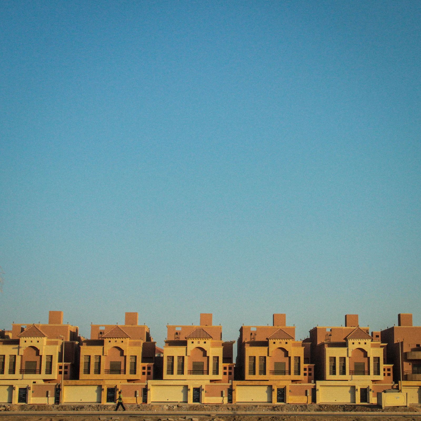 Row of identical houses repeating in a straight line under blue sky