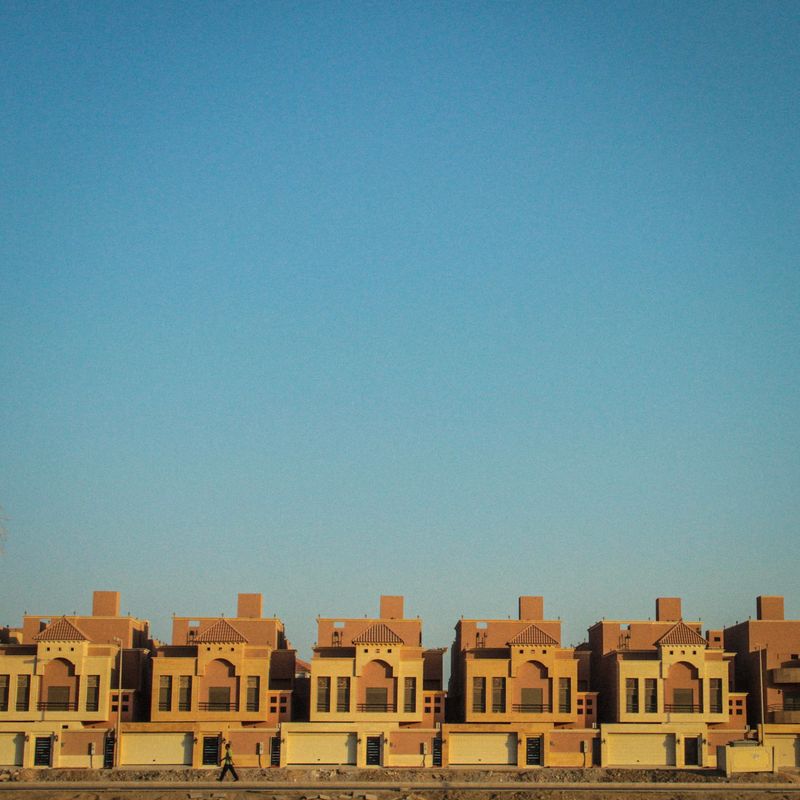 Row of identical houses repeating in a straight line under blue sky