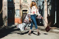 时尚女性自信地大步走在城市小巷的阳光下，展现出别致的风格