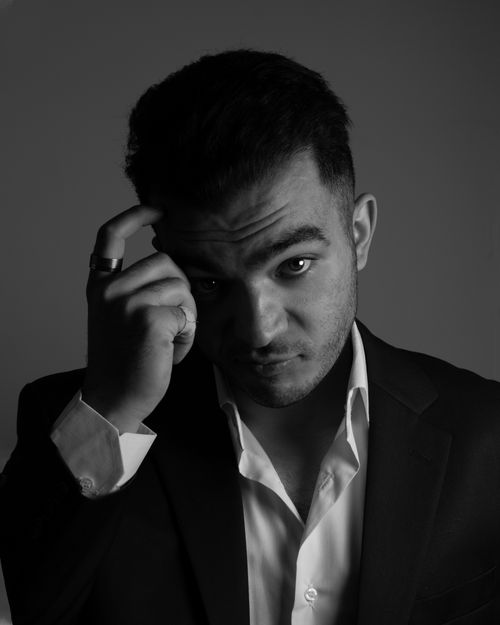 Free Black and white portrait of a confident man in a suit with hand on head. Stock Photo