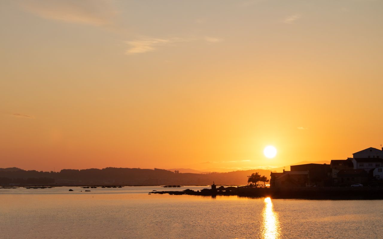 a peaceful sunset over a calm body of water with a silhouette of dista