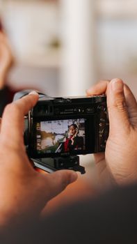 Photographer capturing a woman posing through the digital display of a camera.