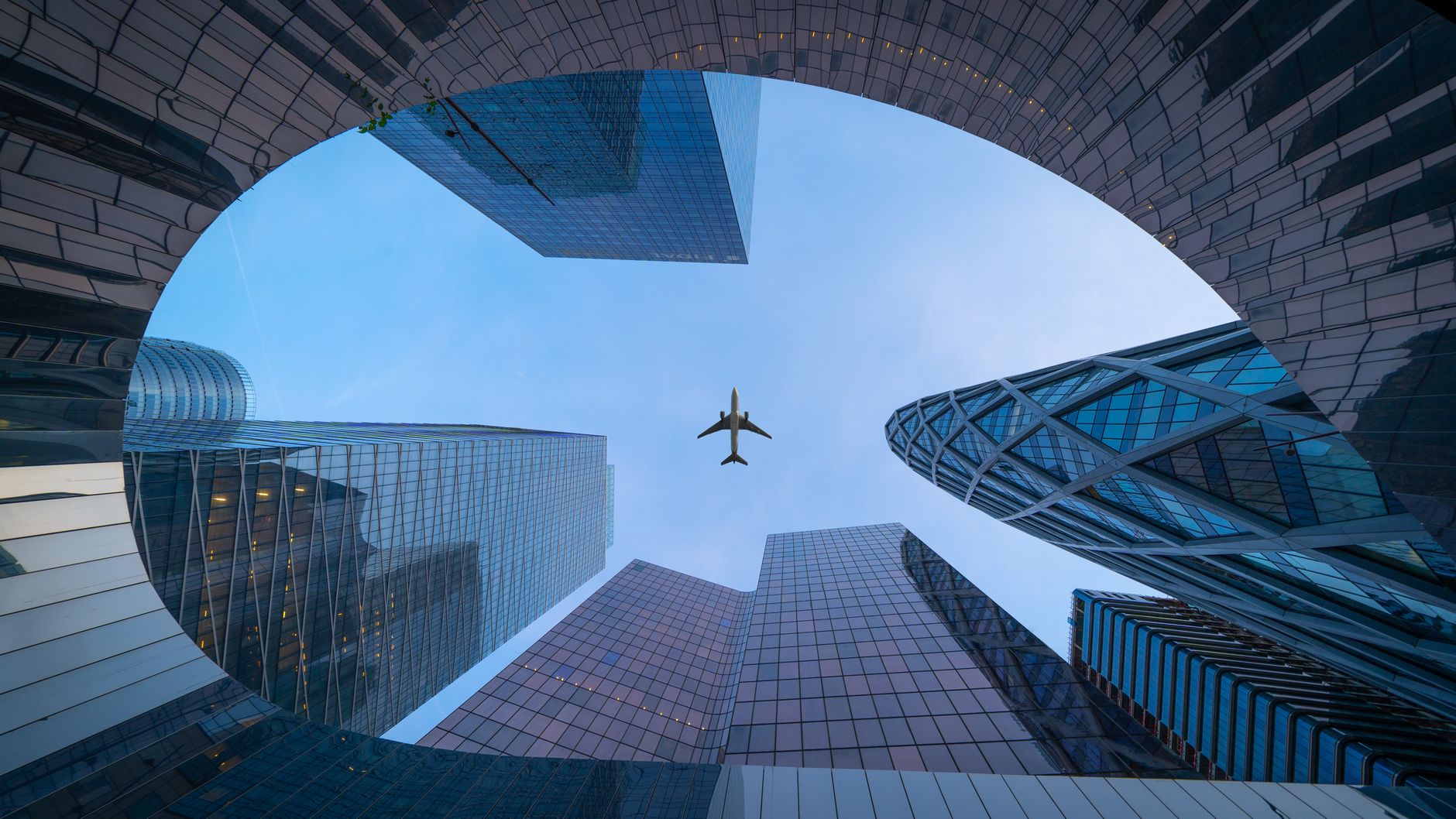 Airplane flying over modern skyscrapers in Paris, showcasing urban architecture.