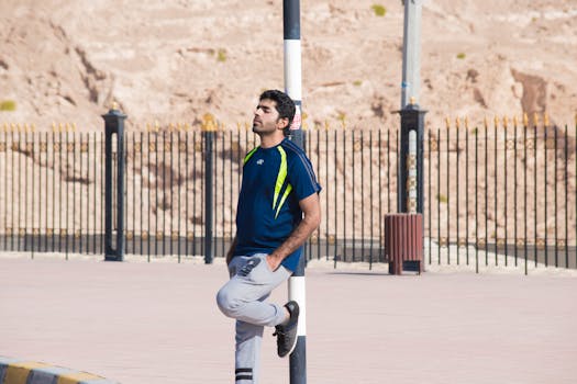 一名穿着运动服的男子靠在城市户外环境中的杆子上