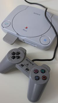 Close-up of a classic Sony PlayStation console and controller on a white background.
