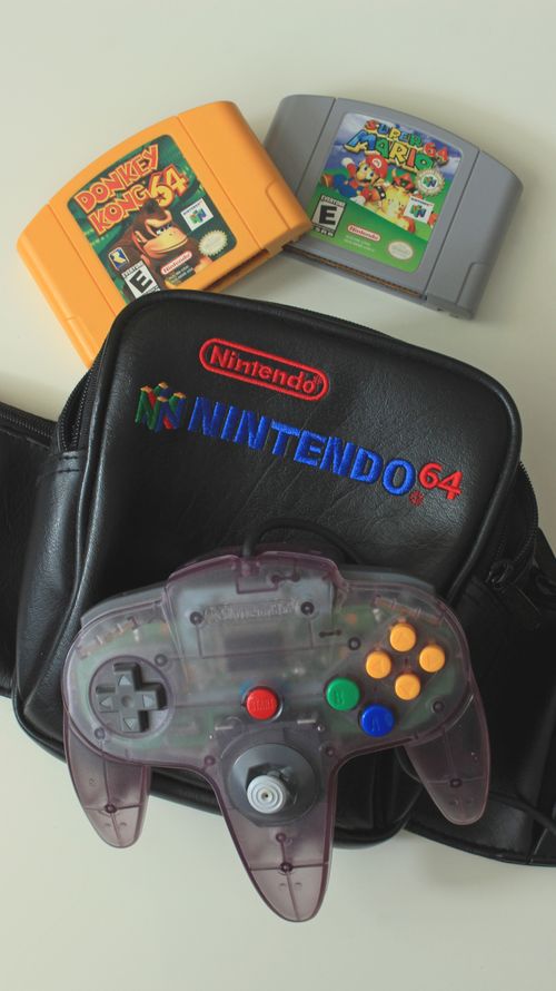 Free Vintage Nintendo 64 controller with game cartridges on a retro gaming bag. Stock Photo