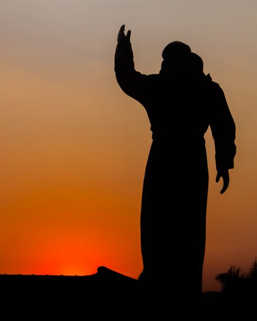Free Silhouette of a statue with hand raised against a vibrant sunset in Antônio Carlos, Brazil. Stock Photo
