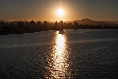 Free Silhouette of Florianópolis cityscape at sunset with sun reflecting on sea water surface. Stock Photo