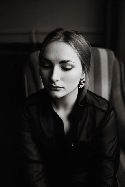 Classic black and white portrait of a woman sitting with eyes closed, exuding elegance.
