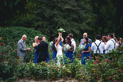 A joyful outdoor garden wedding with bride, groom, and guests celebrating in nature.