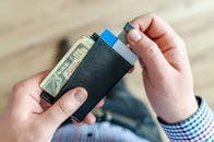 一名男子手持钱包的特写，里面装有现金和信用卡，展示了财务管理的情况