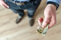 一名男子手持卷起的美元纸币，特写镜头聚焦于现金