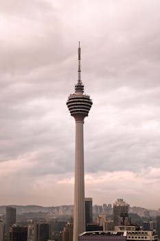 在多云天空的映衬下，吉隆坡标志性塔楼展现出壮丽的现代建筑风貌