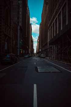 A moody urban street view with towering skyscrapers and a clear sky.