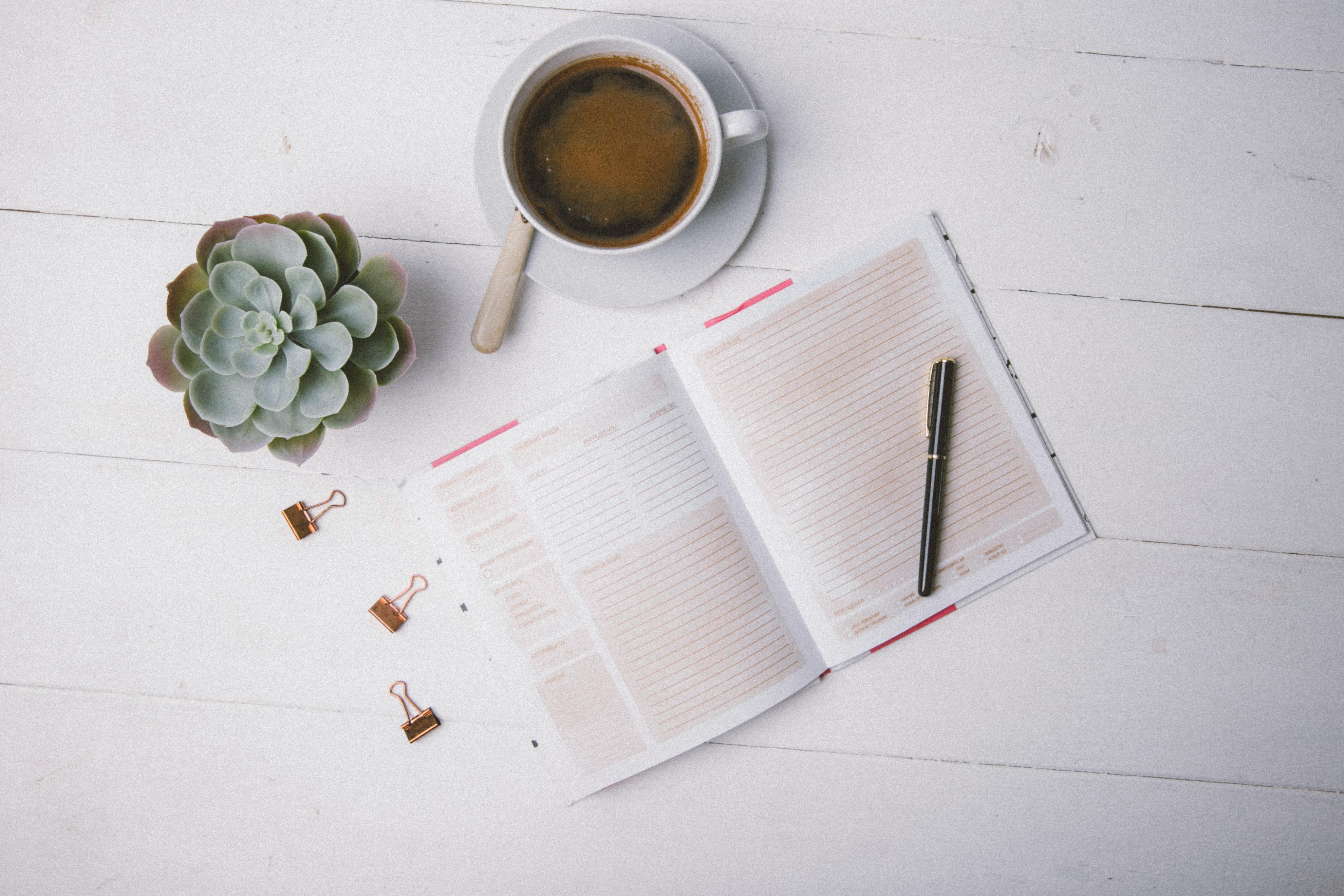 a cup of black coffee besides a journal