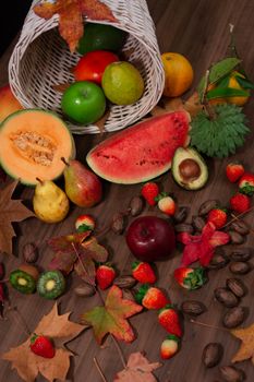 A vibrant display of fruits and nuts with autumn leaves on a wooden table.