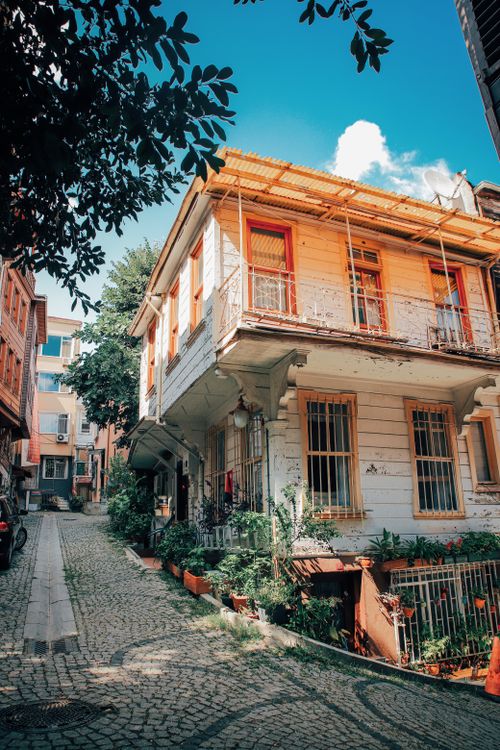 Free Explore a quaint alley with historic houses and lush balconies in a vibrant city setting. Stock Photo