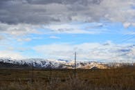 戏剧性的天空下，白雪皑皑的山脉与电力线构成一幅美丽的景色
