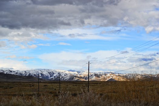 戏剧性的天空下，白雪皑皑的山脉与电力线构成一幅美丽的景色