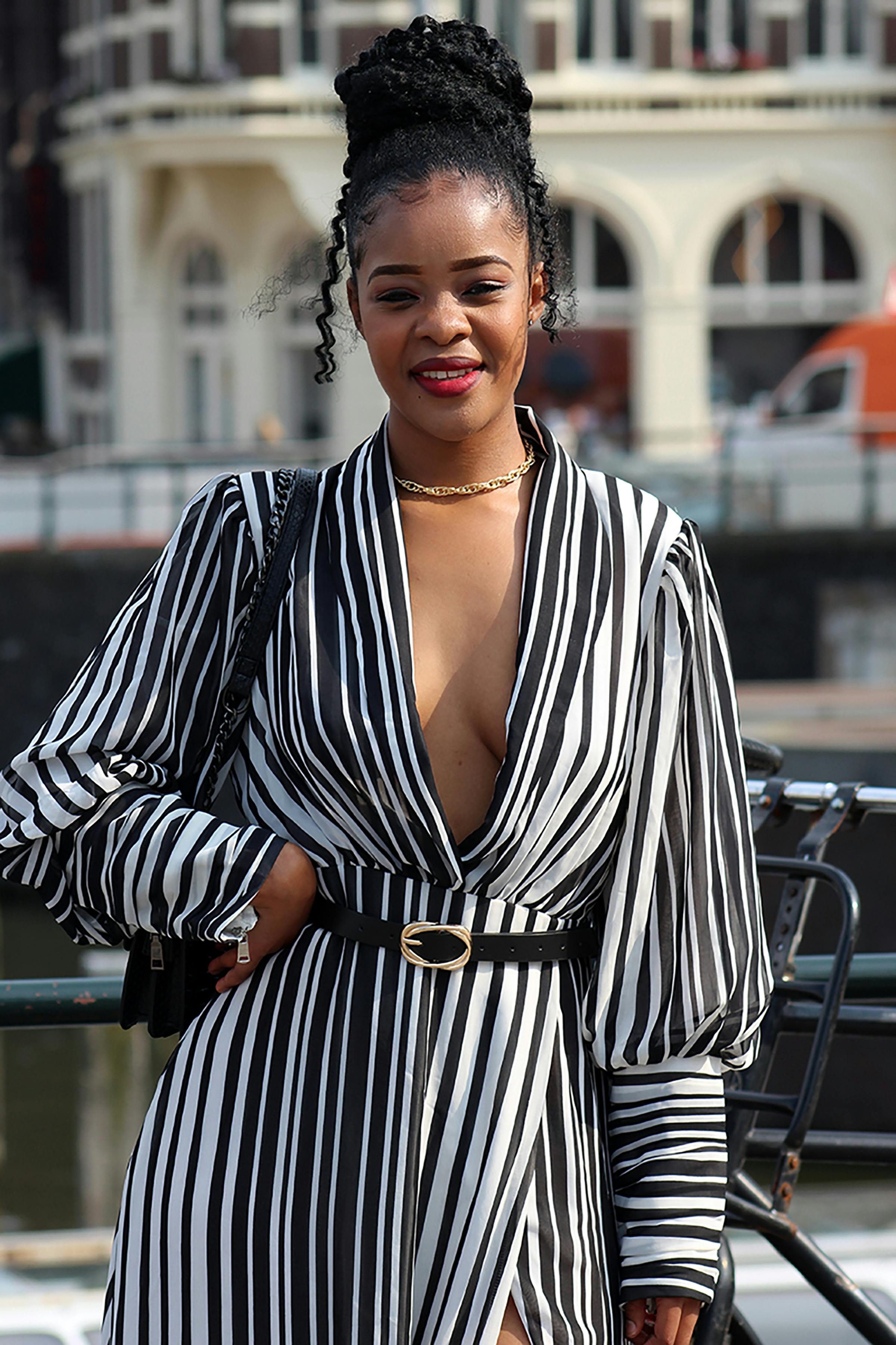 Confident woman in a striped dress posing outdoors in Amsterdam.