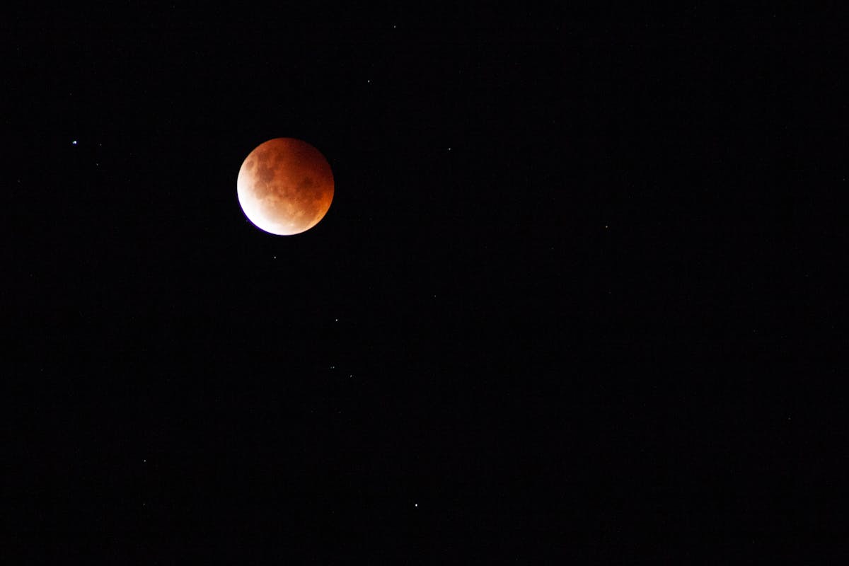 Lunar eclipse with the moon glowing against a starry night sky