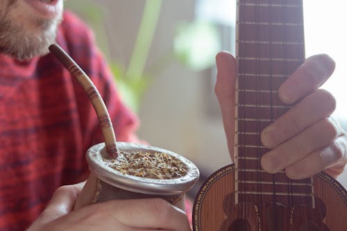 Man Drinking Yerba Mate and Holding a Guitar 