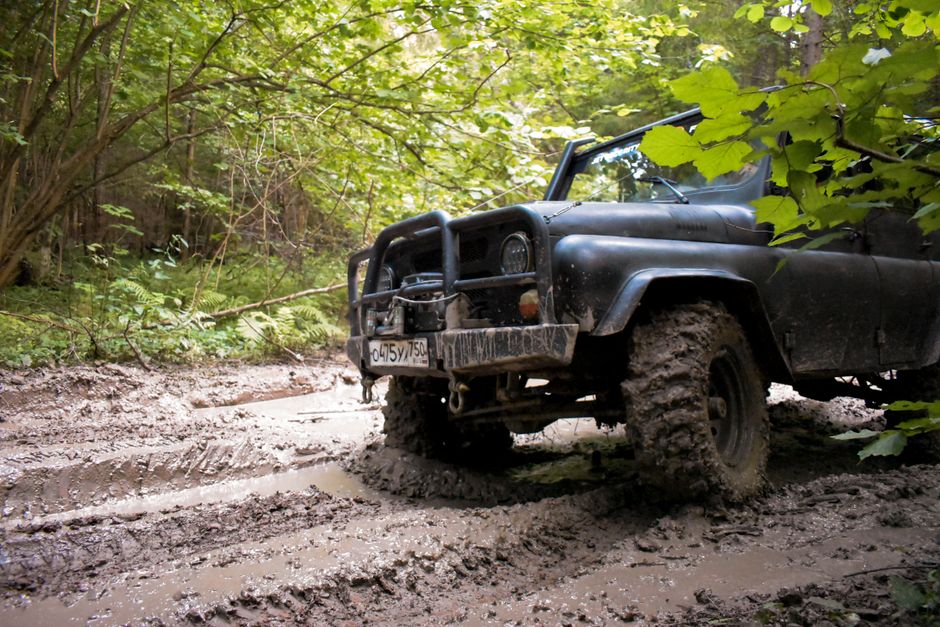 A rugged black SUV on a muddy dirt road in the forest, exemplifying off-road adventure and exploration.