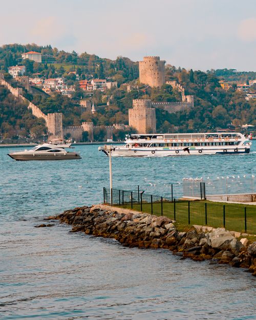 Free Rumeli Fortress along the Bosphorus in Istanbul with boats and lush green hills. Stock Photo