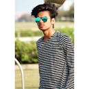 一名年轻人戴着墨镜、穿着条纹衬衫，在户外公园自信地摆姿势