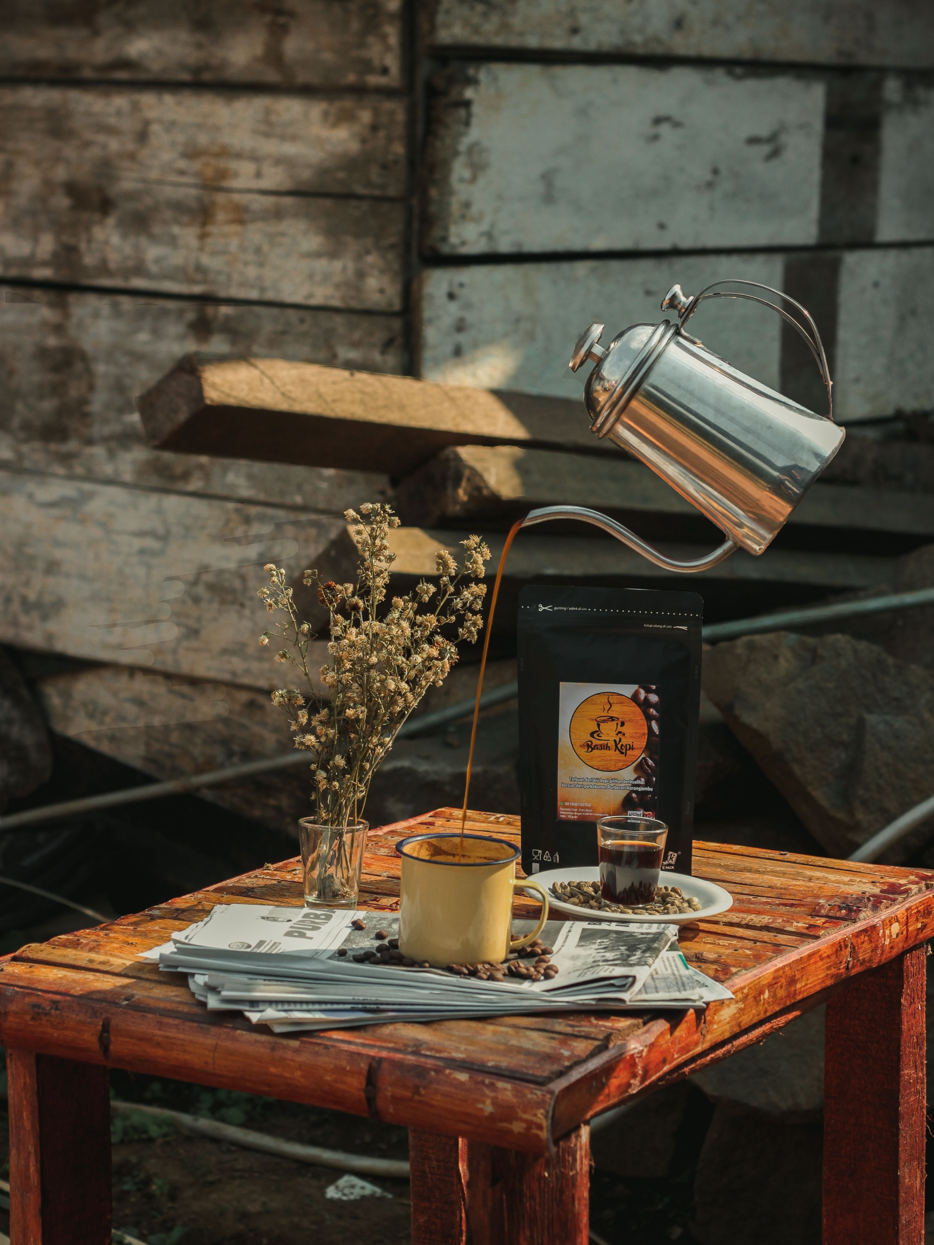 A conceptual still life with coffee pouring into a cup on a wooden table.