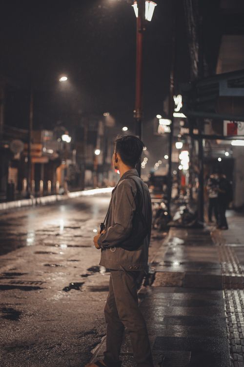 Free A man stands on a wet street illuminated by street lamps in Jawa Barat, Indonesia during nighttime. Stock Photo