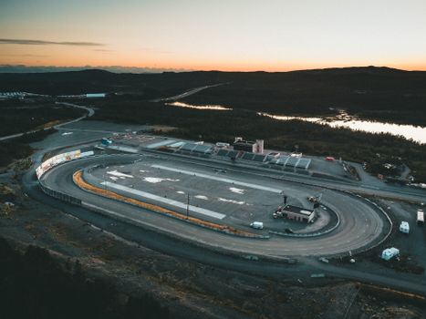 Dramatic aerial view of a deserted racetrack during sunset, showcasing curves and vast landscape.