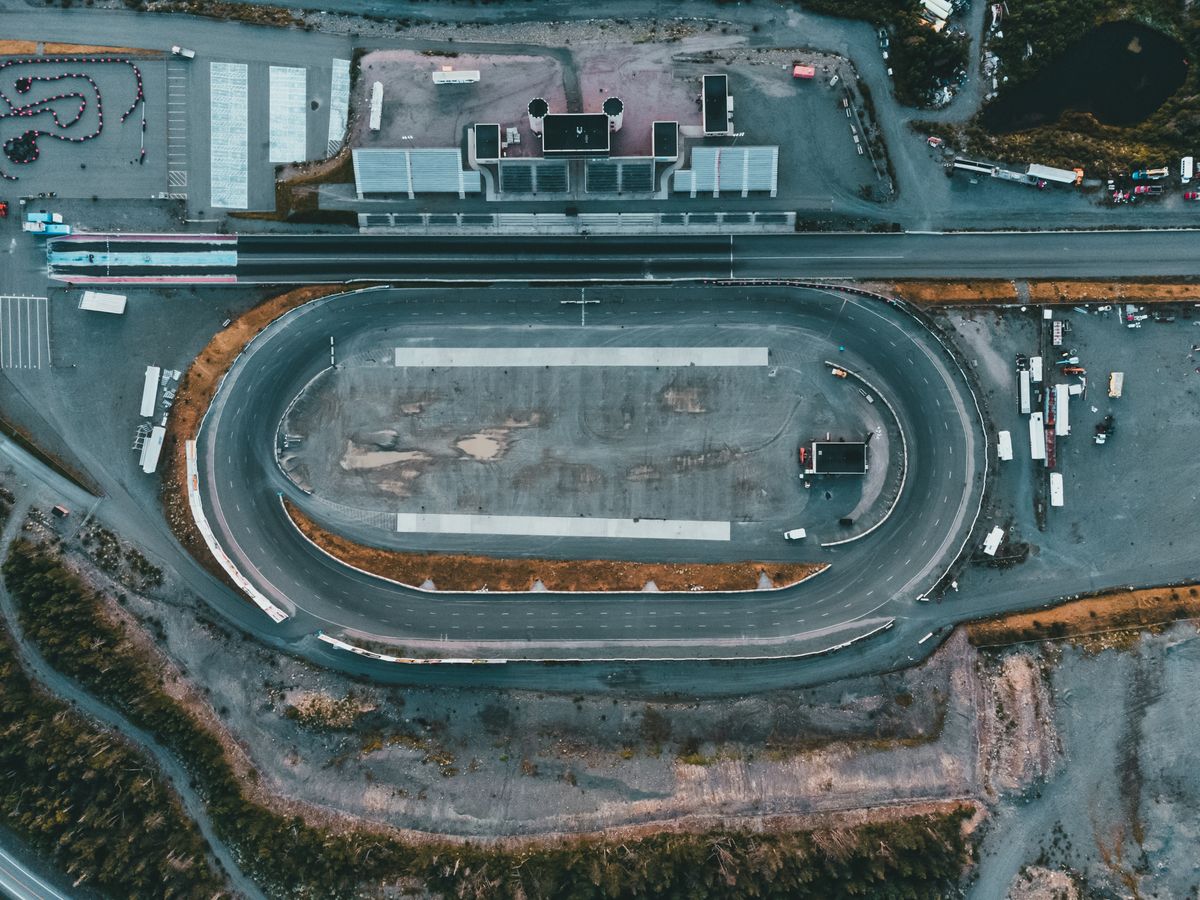 Aerial view of an empty oval racing circuit at dusk — photo by Erik Mclean on Pexels
