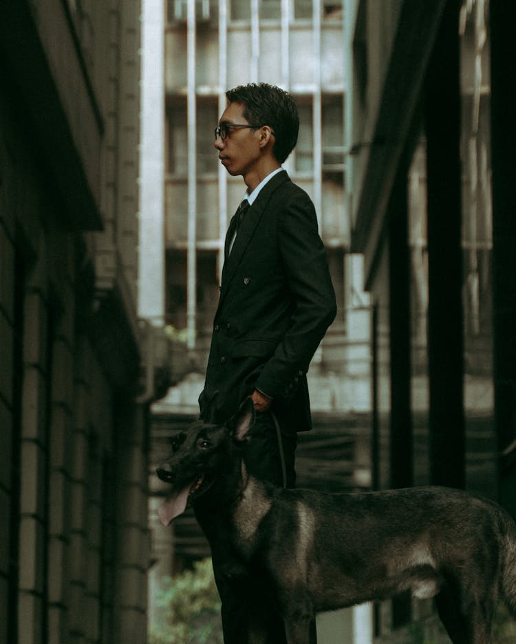 Man In Black Suit Holding A Dog 