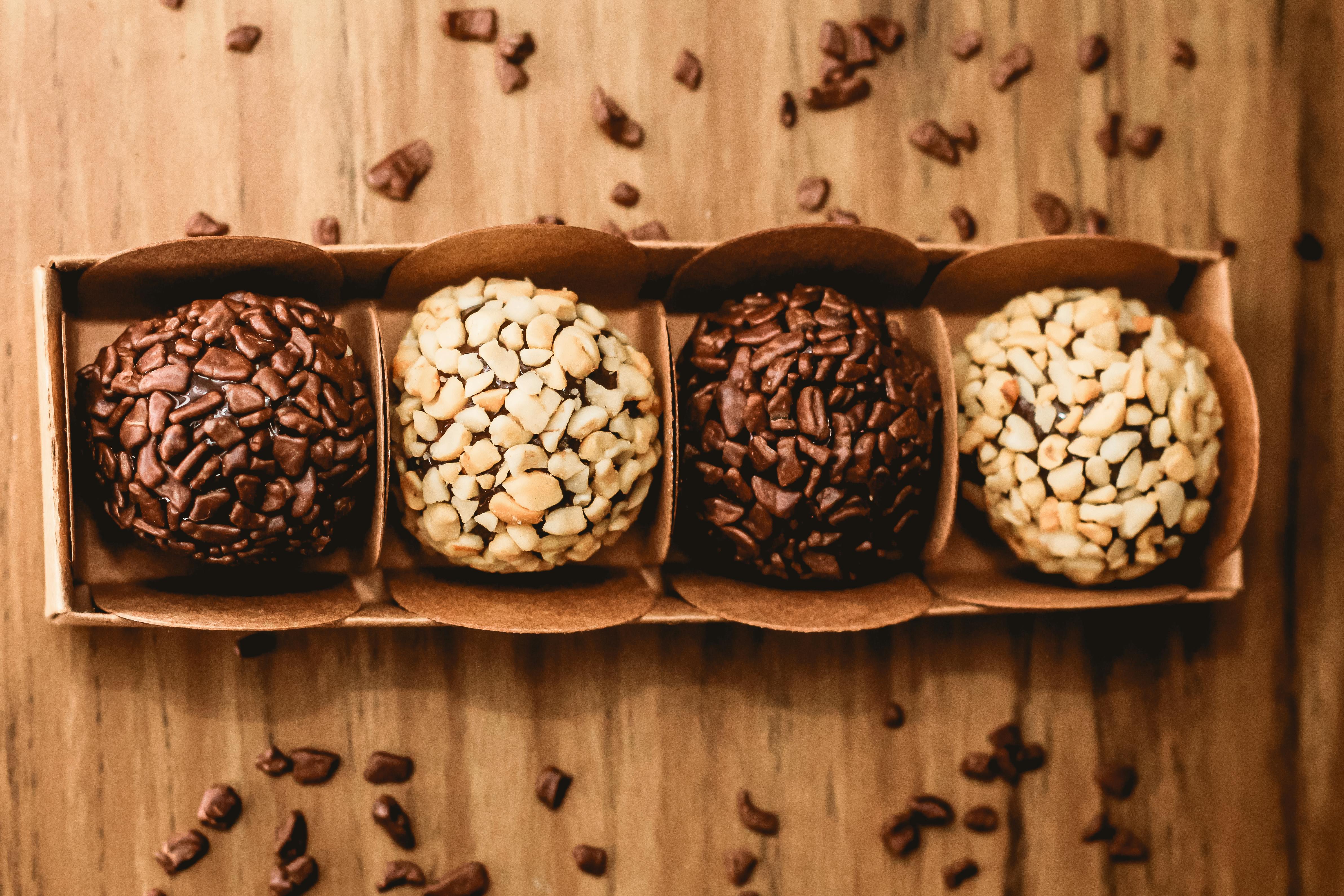 Close-up of assorted chocolate truffles in a box on a wooden surface, showcasing delicious treats.
