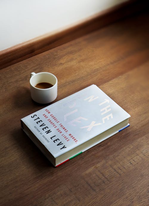 Book and Cup of Coffee on Wooden Surface