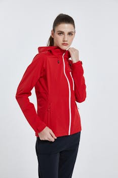 Fashionable young woman in a red jacket posing confidently against a white background.