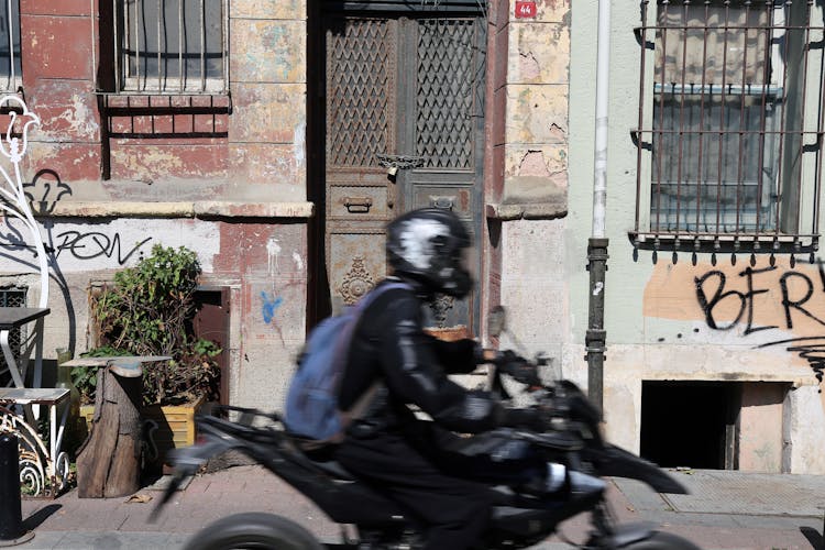 A Person Riding A Motorcycle Past A Condemned Building