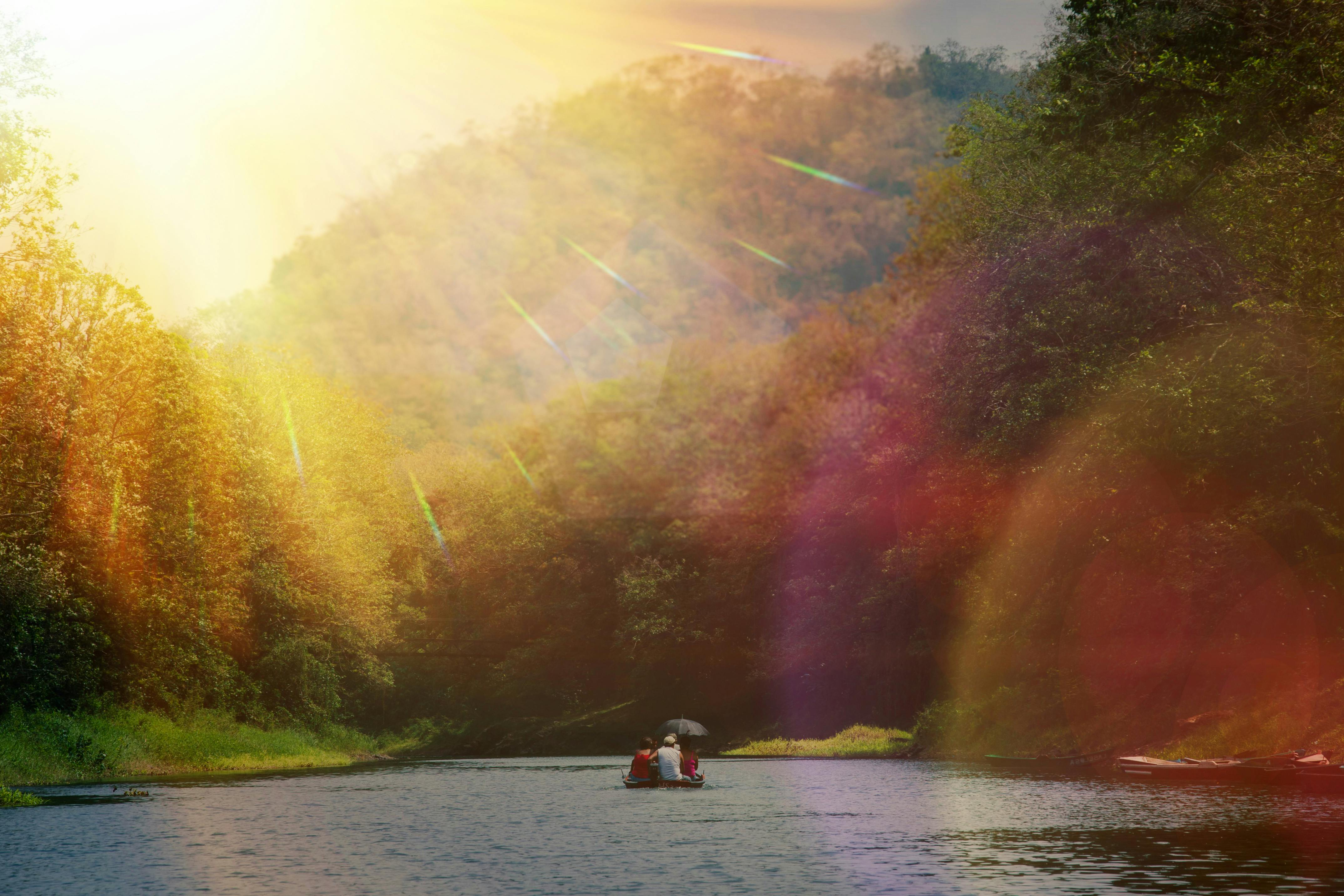 在阳光明媚、充满活力的天空下，乘船宁静地行驶在郁郁葱葱的绿色植物环绕的河流上